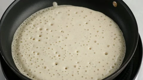 Big round pancake on induction frying pan. Cooking smoke goes up from pancake Video stock 145490612
