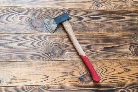 Big rusty ax with long red handle on aged natural wooden background Stock Photos