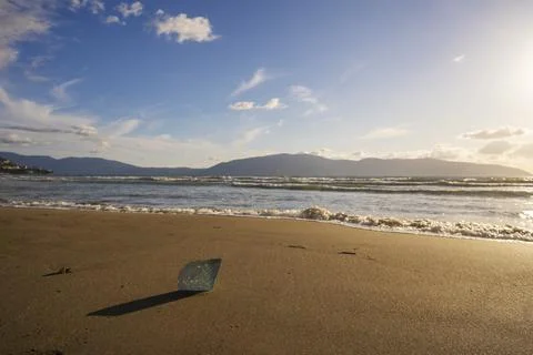Big seashell on the sand on the beach in the back-light of sunset, background Stock Photos