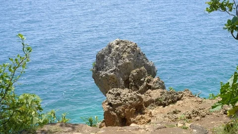 Big sharp stone on a rocky beach with vivid blue water Stockbeeldmateriaal 114988448