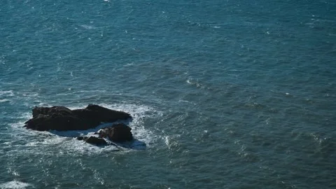 Big sharp stones sticking out from ocean sea water small waves. Top view camera Stock Footage 273794807