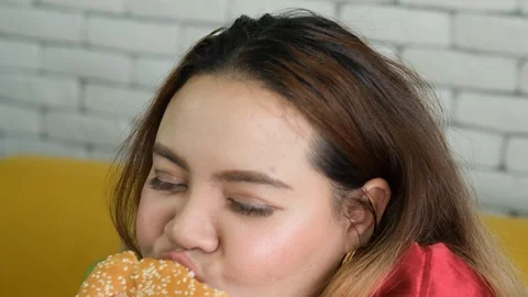Big size girl eats two hamburger with happy emotion in the room with white wall Stock Footage 120723494