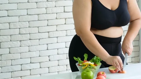 Big size or plus size girl prepares vegetarian salad using knife Stock Footage 120720378