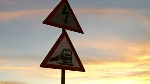 Big sky sunset orange clouds, electricity lines pan to rail crossing road sign Stock Footage 106731470