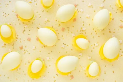 Big small Easter eggs and confetti on yellow background. Egg hunting. Stock Photos