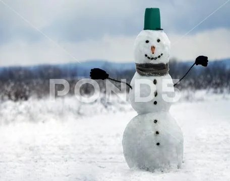 Big smiling snowman with bucket hat, scarf and gloves on white snowy field wi Stock Photos