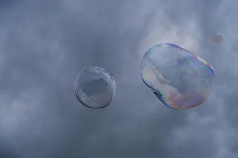 Big soap bubbles against the background of cloudy sky. Stock Photos