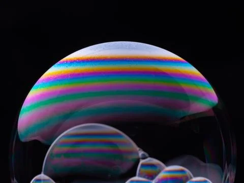 Big soap bubbles with rainbow gradient isolated on black background. Close-up Stock Photos