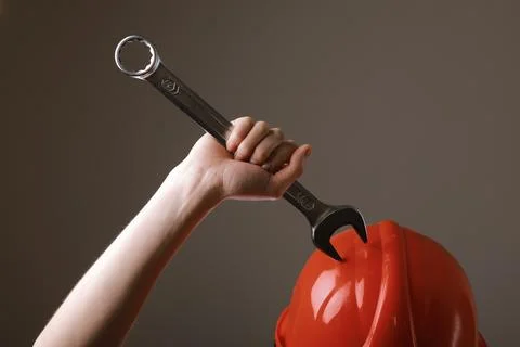 Big spanner in the woman's hand. hand holds a wrench on a gray background. .. Stock Photos
