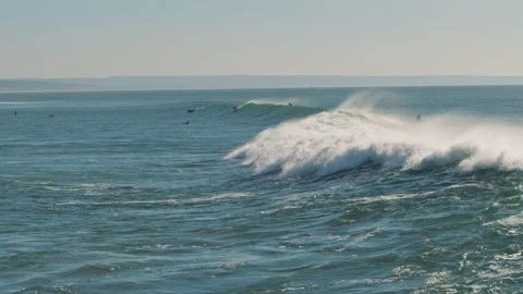 Big splashing ocean wave rushes towards the coast while people surfing Stock Footage 130627895