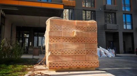 Big stack or red construction bricks on wooden pallet on building site Stock Photos