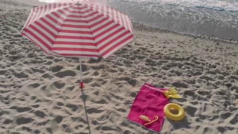 Big striped umbrella installed in sand and beach essentials Stock Footage 170153904