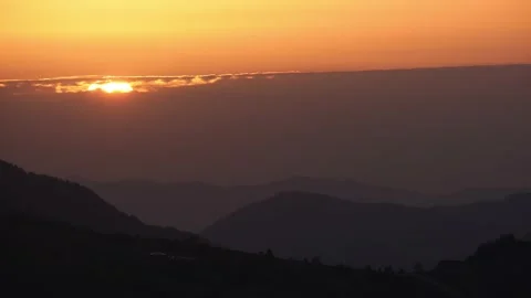 Big sun setting behind a cloud, dusk in a hilly landscape 動画素材 220459897