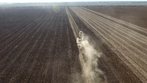 A big tractor plows a huge brown field from bird`s eye perspective in spring Stock Footage 82473613