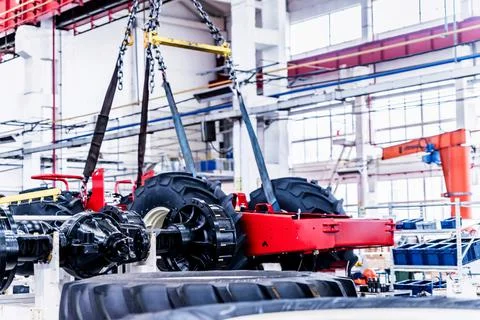 Big tractor wheels installation at assembly room at industrial plant Stock Photos