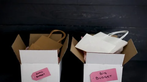 Big vs small budget, different size price tags on delivery parcels with shopp Stock Footage 123389055