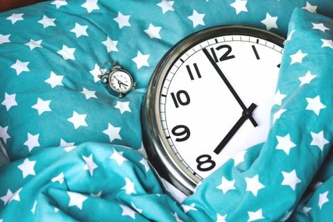Big wall clock in a blue bed and alarm clock Stock Photos