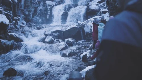 A big waterfall, almost covered in ice. A line of people waits to take pictures. Video stock 126724165