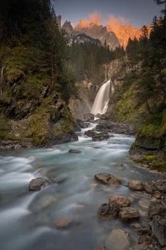 A big waterfall in the valley surrounded by mountains Stock Photos