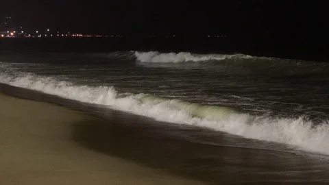 A big wave hits the sandy beach at night. Video stock 119728744