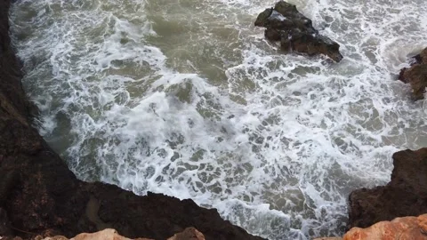 Big wave hitting into rock splashing high with lots of white foam at beach in a Stock Footage 133807641