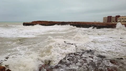 Big wave hitting into rock splashing high with lots of white foam at beach in a Stock Footage 133809896