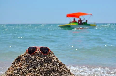 Big waves on the beach, ocean. Red and orange sunglasses lying on a sand slide Stock-Fotos