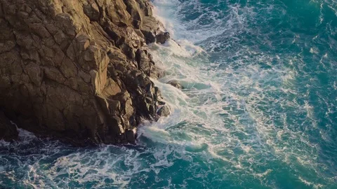 Big waves crash into the black rocks on the sea shore.  Vidéo 127332099