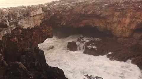 Big waves crashing into an arch-shaped rock formation Stock Footage 146280246
