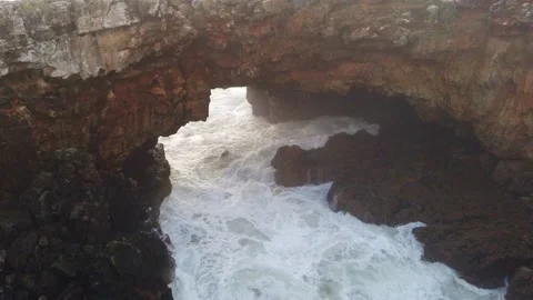 Big waves crashing into an arch-shaped rock formation Stock Footage 146280281