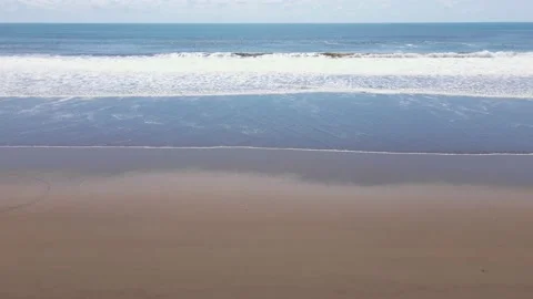 Big waves crashing onto an empty flat beach in broad daylight. High angle Stock Footage 224933330