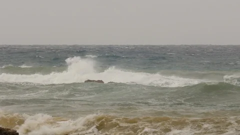 Big waves explode on rocks on the coast during a storm there is surfers in Stock Footage 100097654