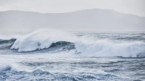 Big waves hit the rocks in rough seas. On a cloudy day. Galicia Spain. Stock Photos