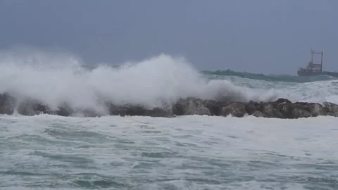 Big waves over wavebreaker, slow motion Stock Footage 183987122
