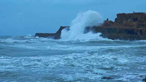 Big waves pile up and hit the rocky shore, taken in slow motion. Stock Footage 135350822