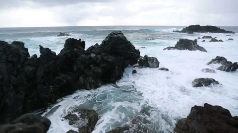 Big waves roll and crash onto the volcanic shore of Easter Island Stock Footage 64257807