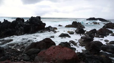 Big waves roll into and crash onto the volcanic rocks Stock Footage 64257847