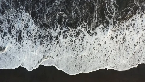 Big waves rolling from above. Drone view of ocean, breaking waves, black sand. Video stock 130068830