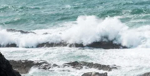 Big waves splashes over the rocks in the ocean Stock Photos