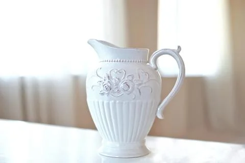 Big white ceramic jug on the table in big bright room Stock Photos
