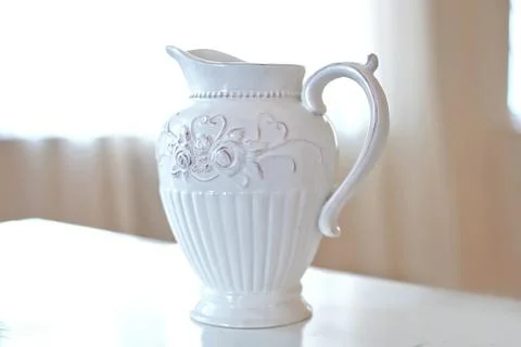 Big white ceramic jug on the table in big bright room Stock Photos
