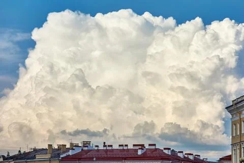 Big white cloud over roofs of houses Stock Photos