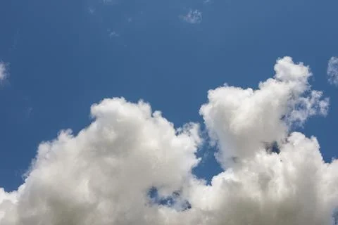 Big white fluffy clouds in summer blue sky background. Perspective, horizon. Stock Photos