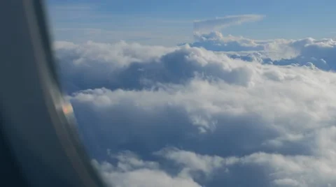 Big white heap clouds on blue sky looking through porthole of flying airplane. Stock-Footage 65005309