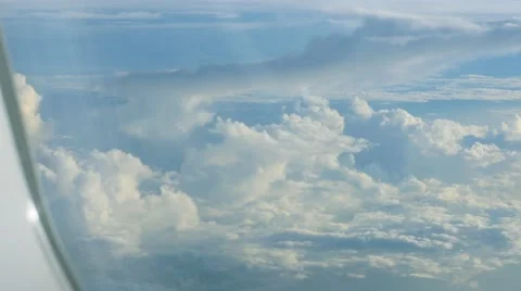 Big white heap clouds on blue sky looking through porthole of flying airplane. Stock Footage 65005812