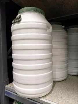 Big white plastic drums arranged neatly on shelves in a hardware store for .. Stock Photos