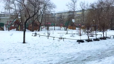 The big white snowflakes fall to the ground next to buildings and trees Stock Footage 173434865
