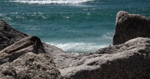Big white waves forming and breaking on sandy beach with rocks in foreground Stock Footage 131112169