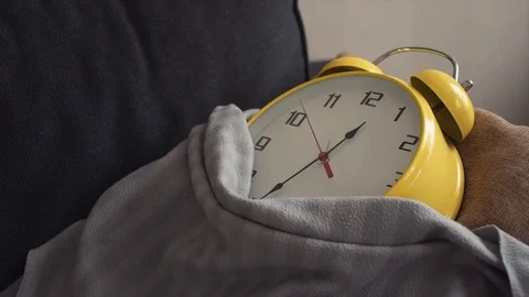 Big yellow clock laying covered a blanket on couch at home. Stock Footage 80814893