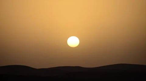 A big yellow sun setting in the front of a golden sky in the Sahara desert Stock Footage 49421780